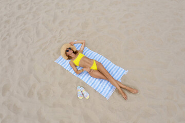 Woman sunbathing on beach towel at sandy coast, aerial view