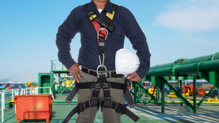 close up worker wearing full safety harness and safey helmet on oil tanker ship for safety concept