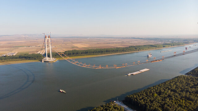 Panoramic aerial drone view from above of the suspended bridge over danube river, under construction, between Braila and Tulcea cities in Romania