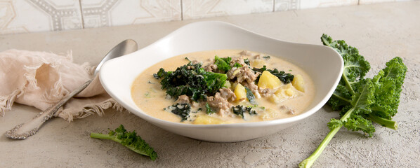 a bowl of traditional Tuscan soup with minced meat and kale on a light table