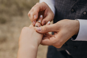 At the wedding ceremony, the groom puts the wedding ring on the bride's finger. Hands of newlyweds with rings close-up. Traditional wedding ceremony with rings donning and an oath of allegiance