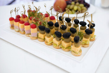 Buffet with focus on canapes made from cheese, meat and olives with tomatoes. Delicious treat for guests in a restaurant or at home