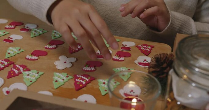 Asia woman enjoy fun make craft gift for night party tasty snack cooking recipe on table in good warm relax time. Cute smile gingerman mold shape bakery icing sugar glaze with red green white color.