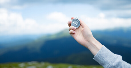 Traveler hand holds compass against beautiful Carpathian mountains view. Horizontal banner with...