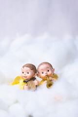 Two figures of angels on cotton simulating clouds. Christmas greeting concept. Copy Space