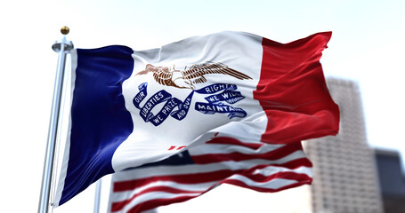 the flag of the US state of Iowa waving in the wind with the American flag blurred in the background