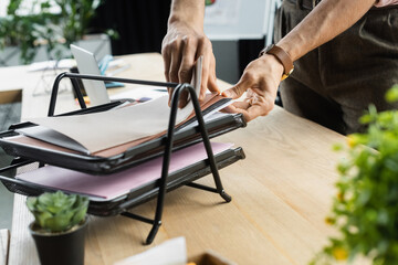 Cropped view of manager searching papers on table in office