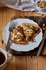 Pancakes with walnuts, chocolate and mascarpone cream. Wooden background, side view.