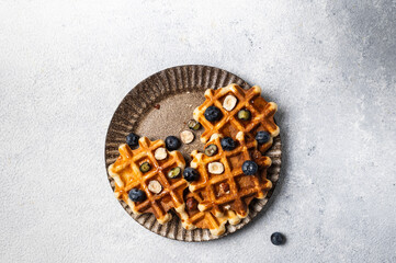 Freshly made belgian waffles with blueberry and hazelnut. Waffles with honey and berry. Place for text. Copy space. Classic sweet breakfast