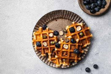 Freshly made belgian waffles with blueberry and hazelnut. Waffles with honey and berry. Place for text. Copy space. Classic sweet breakfast