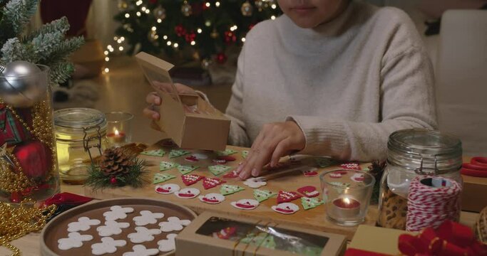 Asia woman enjoy fun make craft gift for night party tasty snack cooking recipe on table in good warm relax time. Cute smile gingerman mold shape bakery icing sugar glaze with red green white color.