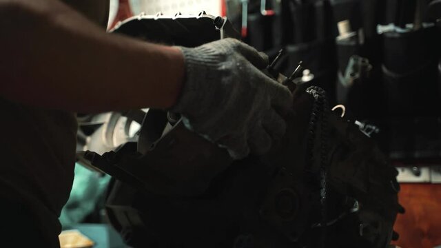 a man in work gloves installs a variator box on an ATV engine