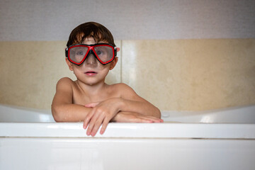 Portrait young boy leaning on bathtub edge wearing a diving mask