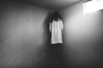 Scary girl in nightgown hovering in the corner of room