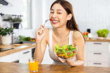Close up Happy Asian healthy woman smiled and holding  vegetable salad and eat small tomato to diet and eat clean food - obrazy, fototapety, plakaty