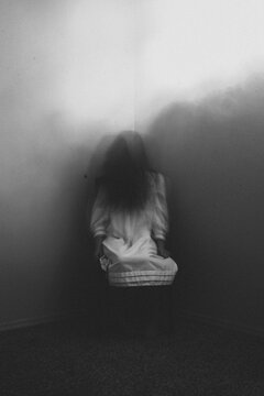Spooky ghost girl sitting in corner of room at home