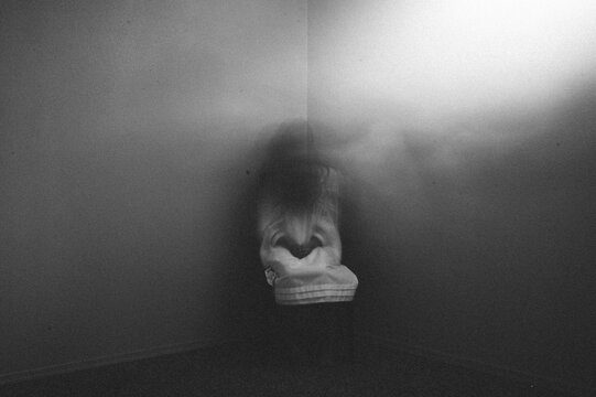 Ghost girl sitting in dark foggy corner of haunted house