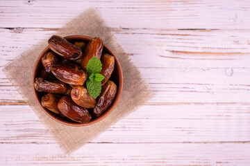 Sweet dates in a bowl on a white wooden background. Flat lay. Copy space.