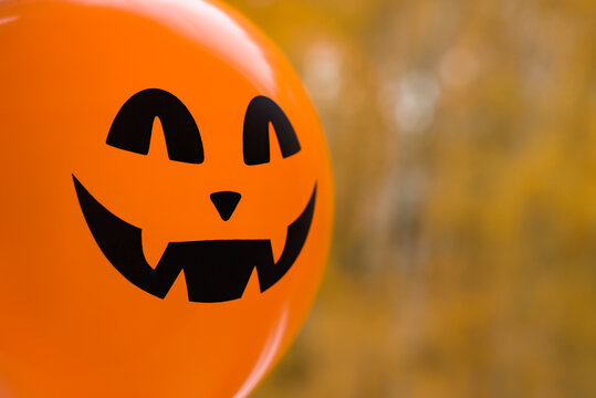 Halloween holiday decoration and party concept. A mystical orange balloon with a terrible grin.