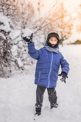 a happy child plays snowballs against the background of a snow forest