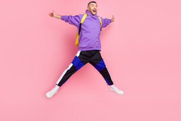 Fototapeta na wymiar Full size photo of funny millennial brunet guy jump wear hoodie bag pants shoes isolated on pink background
