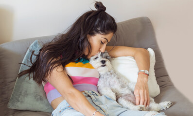 Young Woman Hugging and Kissing her White Havanese Dog at Home 