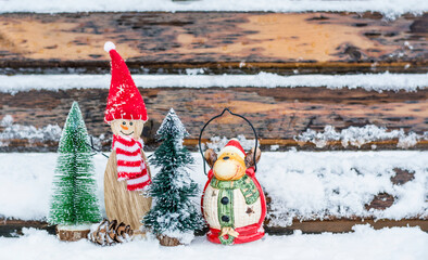 Merry Christmas greeting card with wooden snowman and small trees in the snow