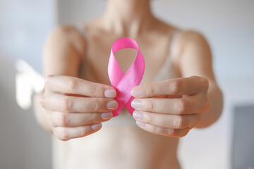 Unrecognized Female In Beige Lingerie Holding a Pink Ribbon. Breast Cancer Awareness. Photo for Support and Health Care