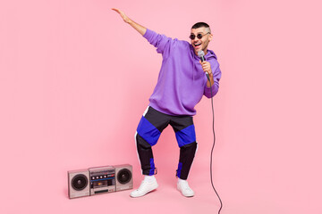 Full body photo of young excited guy street artist sing mic pop music boombox isolated over pink...