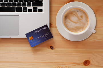 Credit card on Laptop computer and White latte coffee mug, Concept of Online shopping and payment, top view.