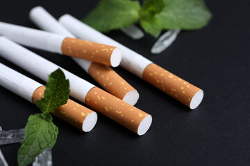 Cigarettes, menthol crystals and mint on black background, closeup