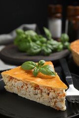 Piece of delicious pie with meat and basil in plate, closeup