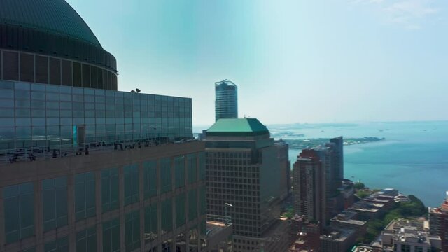 Helicopter flying fast around waterfront building at lower Manhattan, Wall street district with Hudson river and liberty island view in distance. Panoramic overview on World Trade center New York city