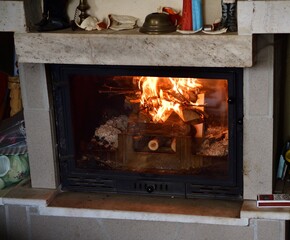 Flames of a burning fire in a fireplace insert in a cottage