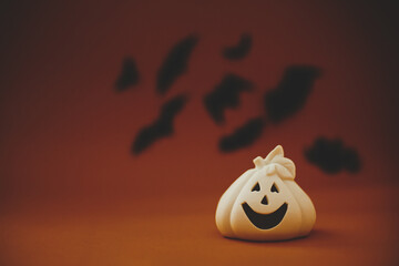 Halloween background. Jack o lantern pumpkin decoration on dark orange background with flying black...