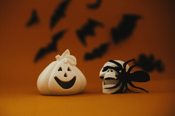 Halloween background. Jack o lantern pumpkin decoration and skull with spider on dark orange...