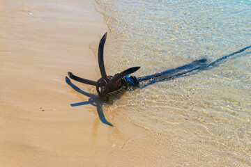 Small boat anchor on a shore of ocean