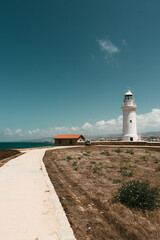 Sandy way to the white lighthouse. Characteristic landmark on the coastline of Cyprus. 