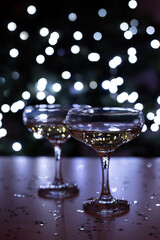 Two glasses of champagne on a background of bokeh lights at night, Christmas concept.
