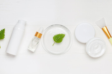 Natural cosmetics with nettle leaves. Top view. Cream, serum, bottle lotion.