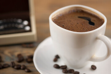 A cup of coffee with bow tie and gift box on old wooden table with some beans. Father day card.