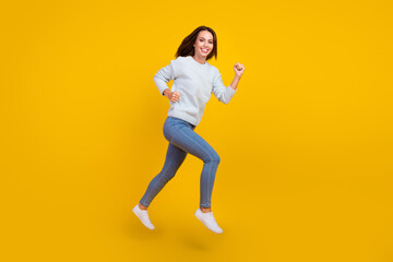 Fototapeta na wymiar Full size photo of cheerful happy young woman jump up run sale good mood isolated on yellow color background