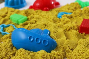 Bright kinetic sand and toys on table, closeup