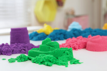 Fototapeta na wymiar Colorful kinetic sand on white table indoors