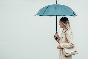 Businesswoman with umbrella walking down city street during rain