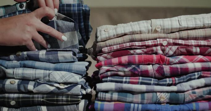 Women's hands sort through a stack of men's shirts