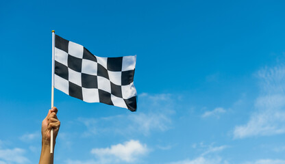 Hand holding checkered race flag in the air