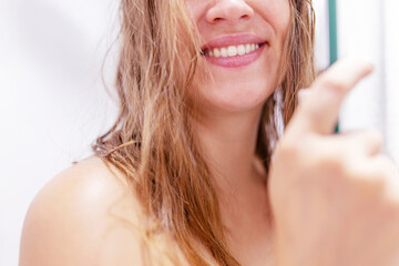 Close up half face cropped portrait of smiling woman's with wet hair after shower in shower cabin...