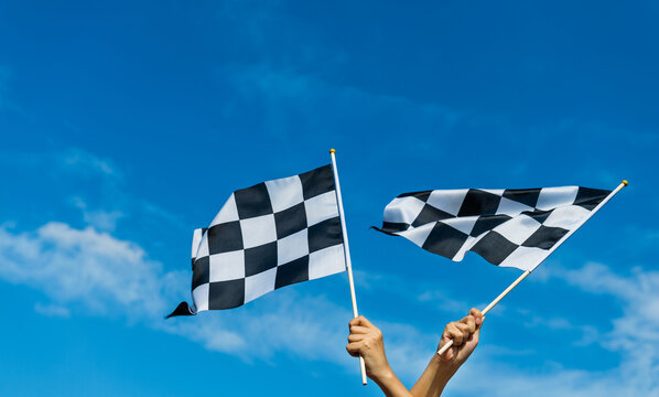 Hand holding checkered race flag in the air