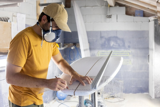 Surfboard Modeling Workshop - Man perfecting the modeling of a surfboard - Powered by Adobe